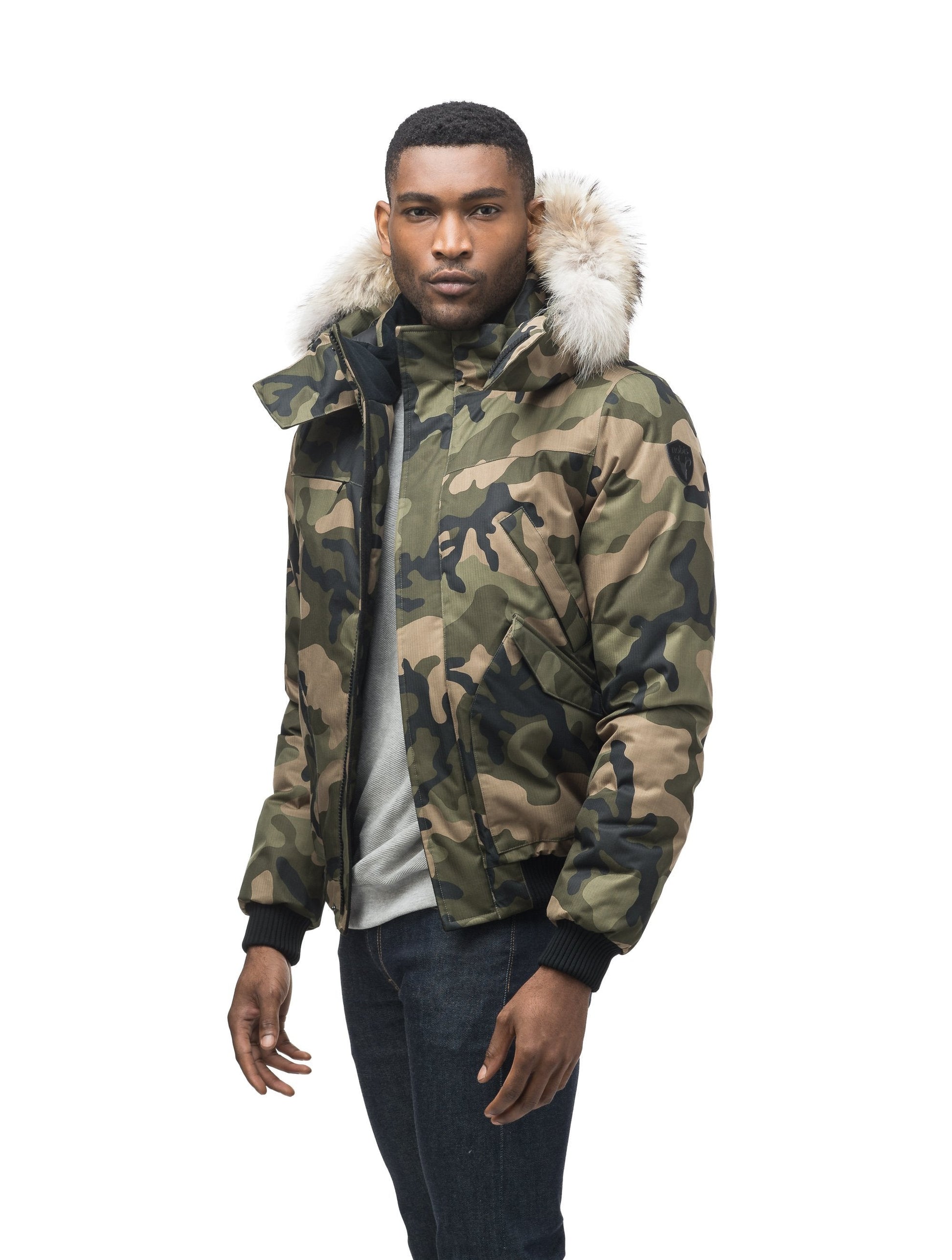 Men's classic down filled bomber jacket with a down filled hood that features a removable coyote fur trim and concealed moldable framing wire in Camo