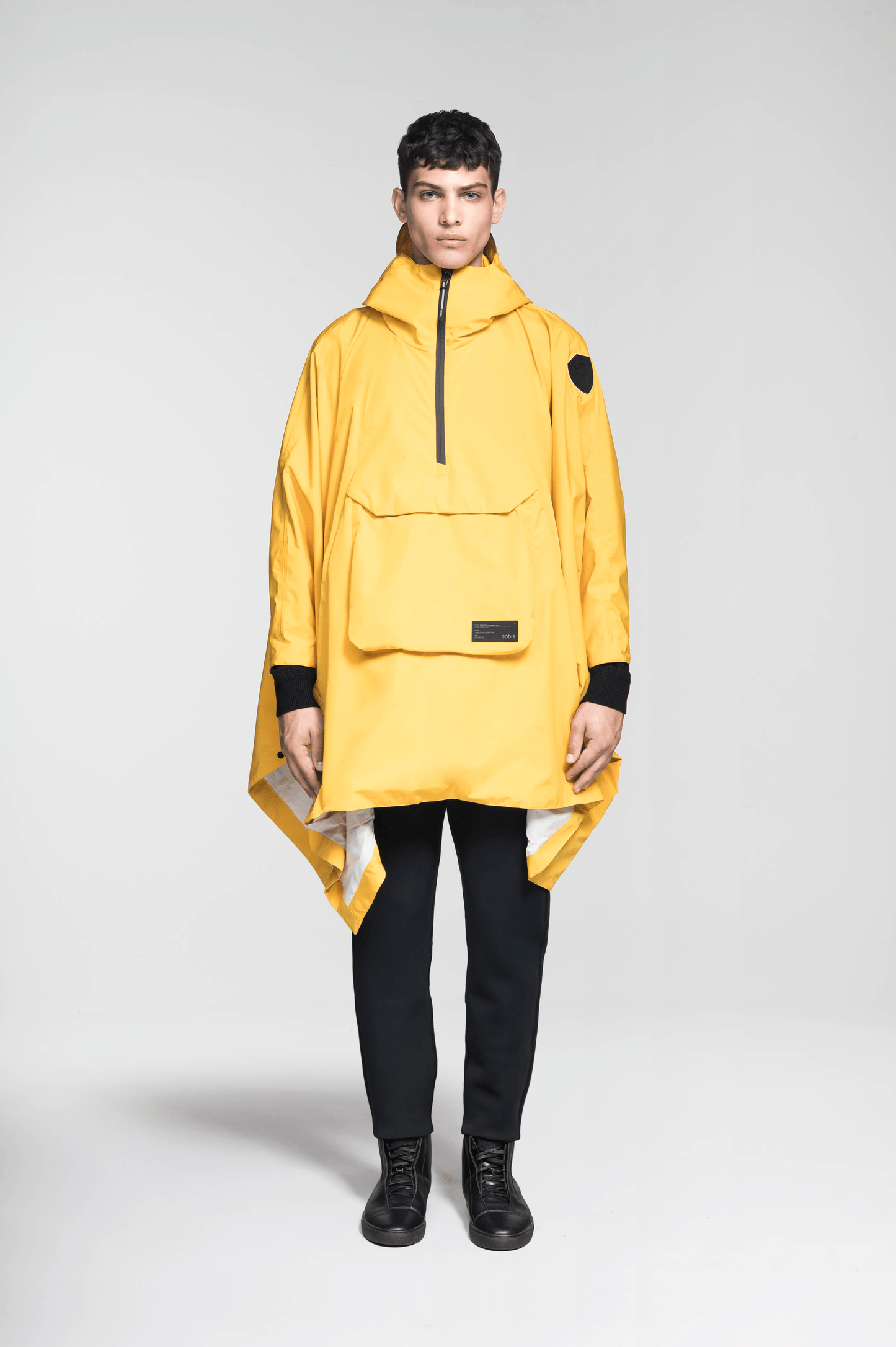 Hydra Unisex Performance Poncho in thigh length, non-removable hood, vertical half-zipper along centre front collar, hidden side-entry waist zipper pockets, adjustable webbing straps and snap closure cuffs, and packable to front kangaroo pocket with flap opening, in Old Gold