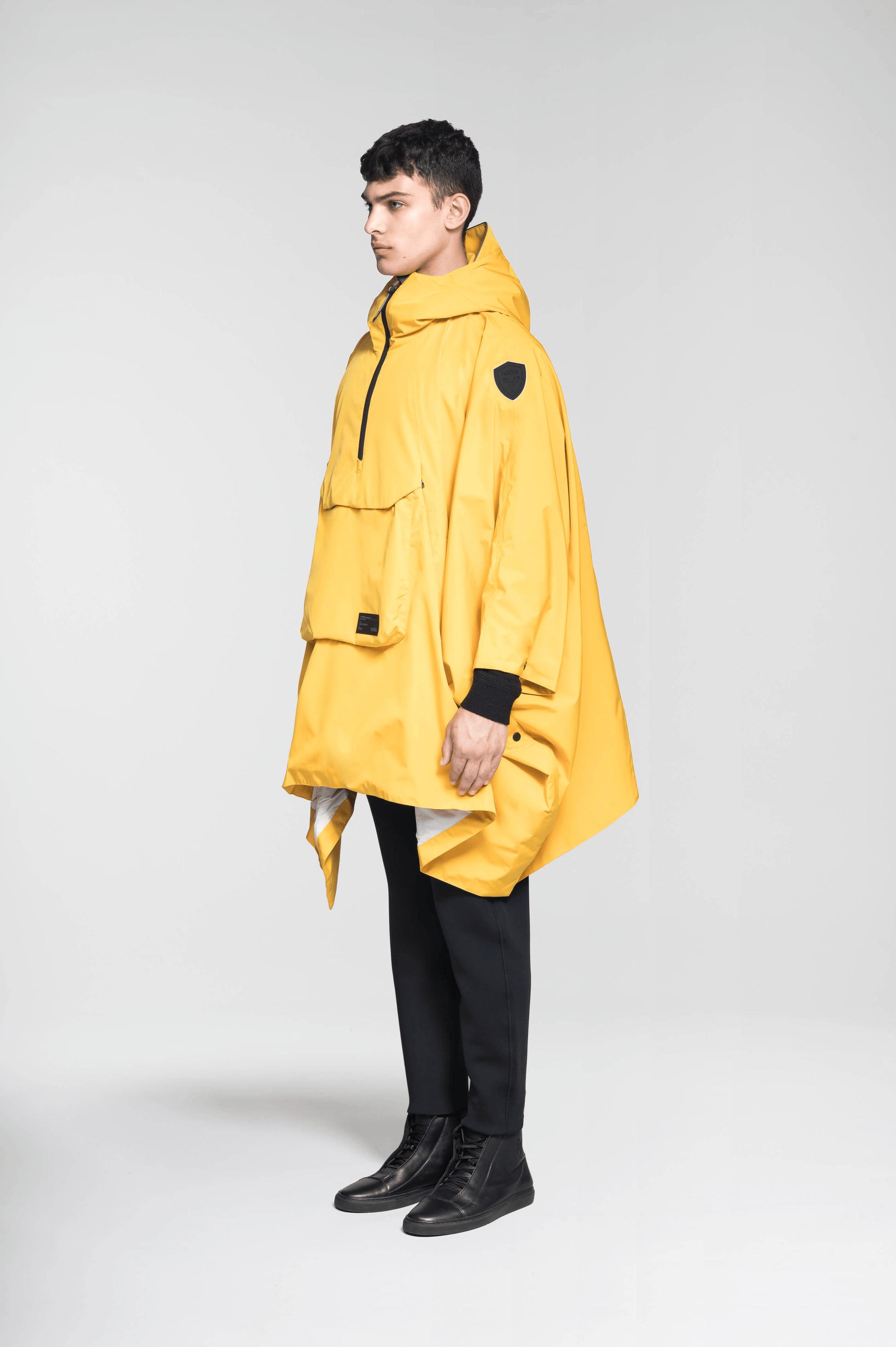 Hydra Unisex Performance Poncho in thigh length, non-removable hood, vertical half-zipper along centre front collar, hidden side-entry waist zipper pockets, adjustable webbing straps and snap closure cuffs, and packable to front kangaroo pocket with flap opening, in Old Gold