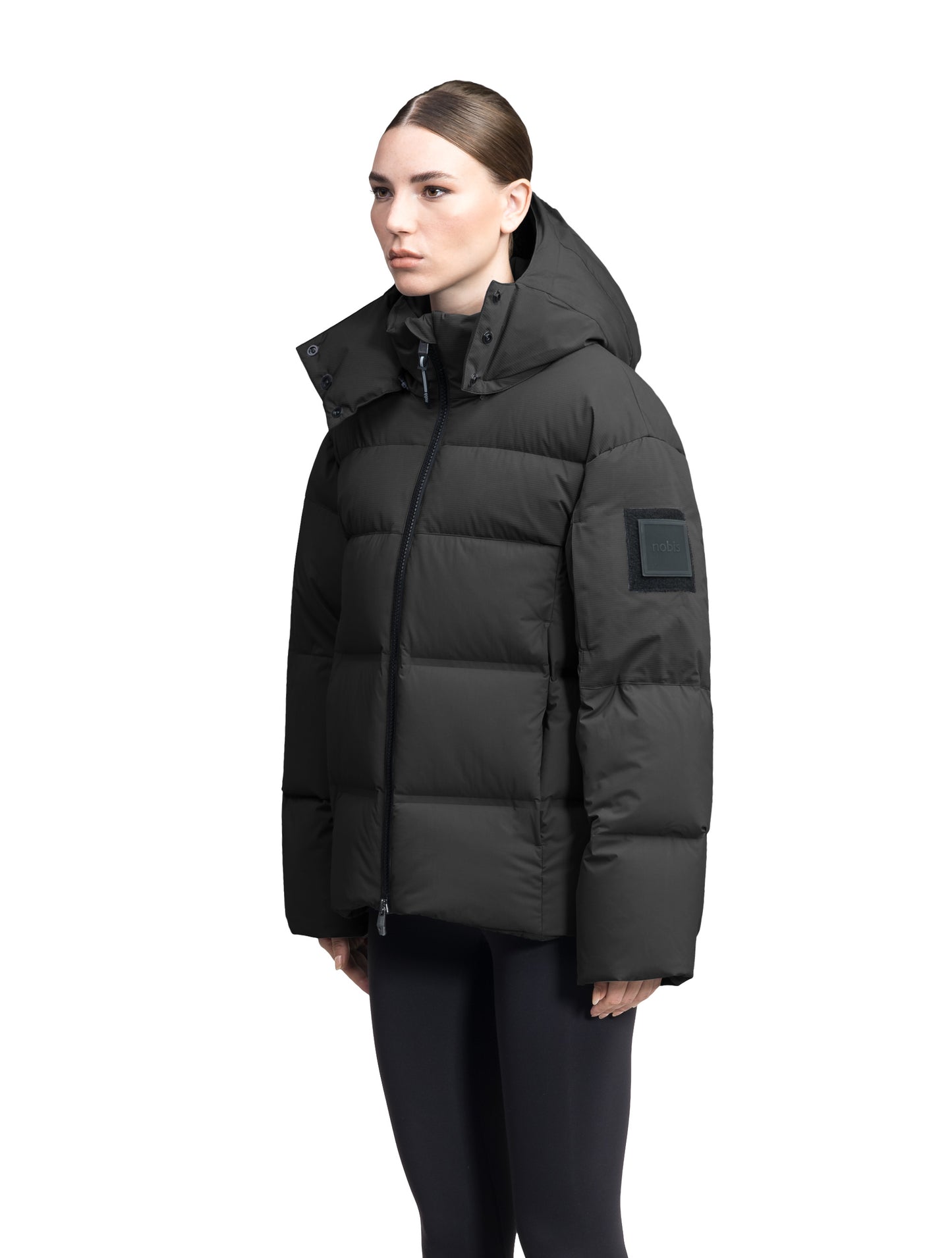 Una Ladies Performance Puffer in hip length, Technical Taffeta and Durable Stretch Ripstop fabrication, Premium Canadian White Duck Down insulation, removable down filled hood, centre front two-way zipper, and side-entry pockets at waist, in Black